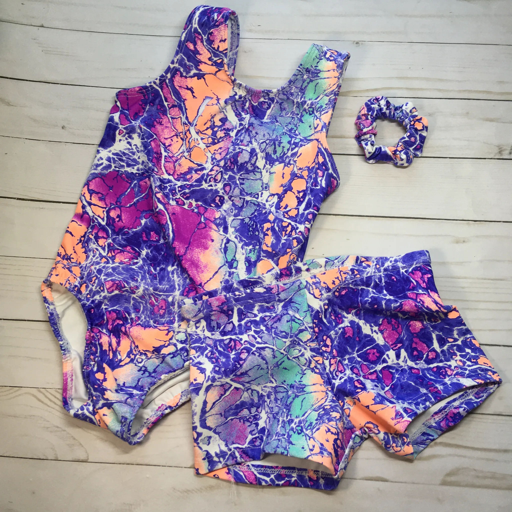 toddler girls tank gymnastics leotard with matching shorts and scrunchie.  a colorful crackle print with pinks, purple, turquoise and light orange 