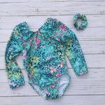 Load image into Gallery viewer, Girls Gymnastics or Dance long sleeve leotard in soft pastel floral pattern on light teal background color. Has a matching hair scrunchie.
