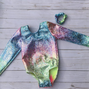 Girls long sleeve leotard for gymnastics or dance in a Pastel tie dye with shiny silver overlay. Matching scrunchie included.
