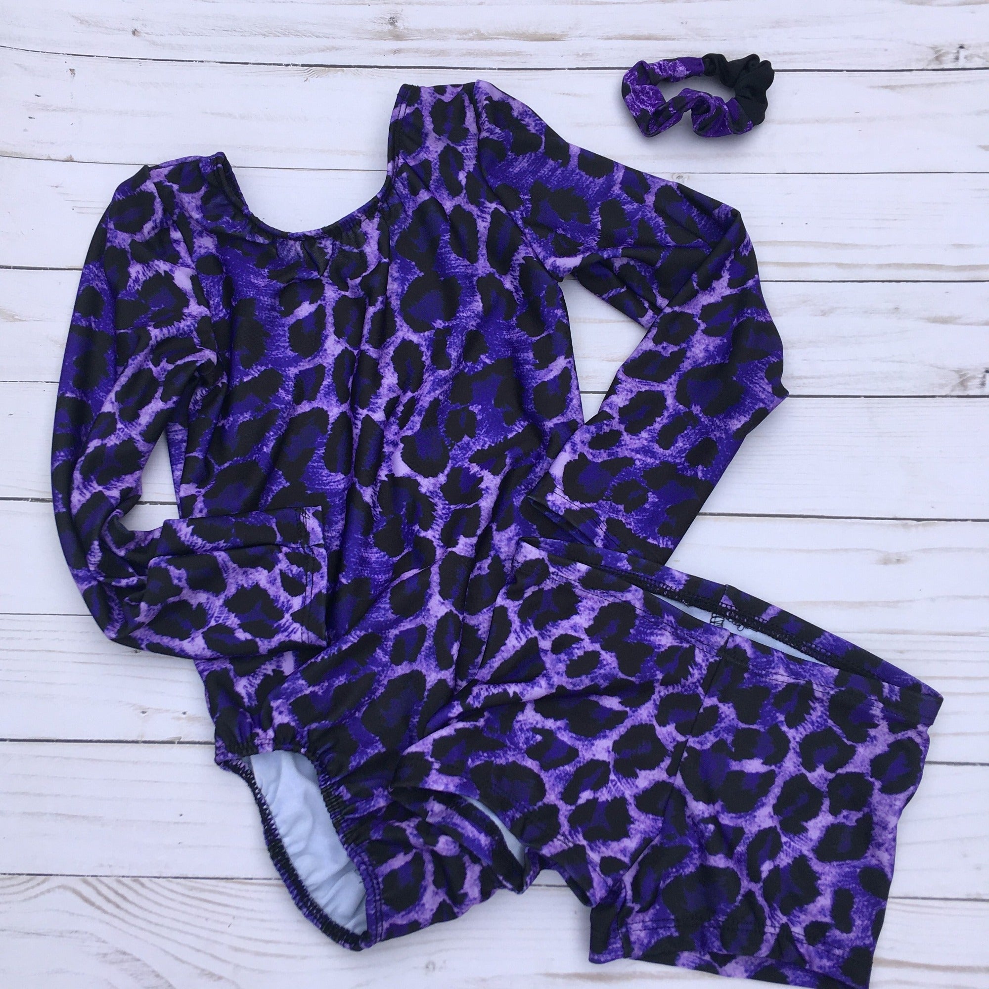 long sleeve gymnastics or dance leotard in purple and black leopard print with matching shorts and scrunchie