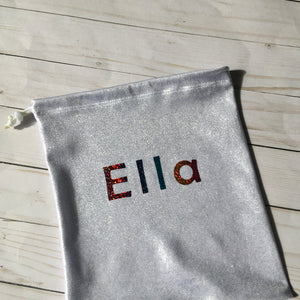gymnastics grip bag in shiny silver fabric with rainbow sparkle personalization in block letters