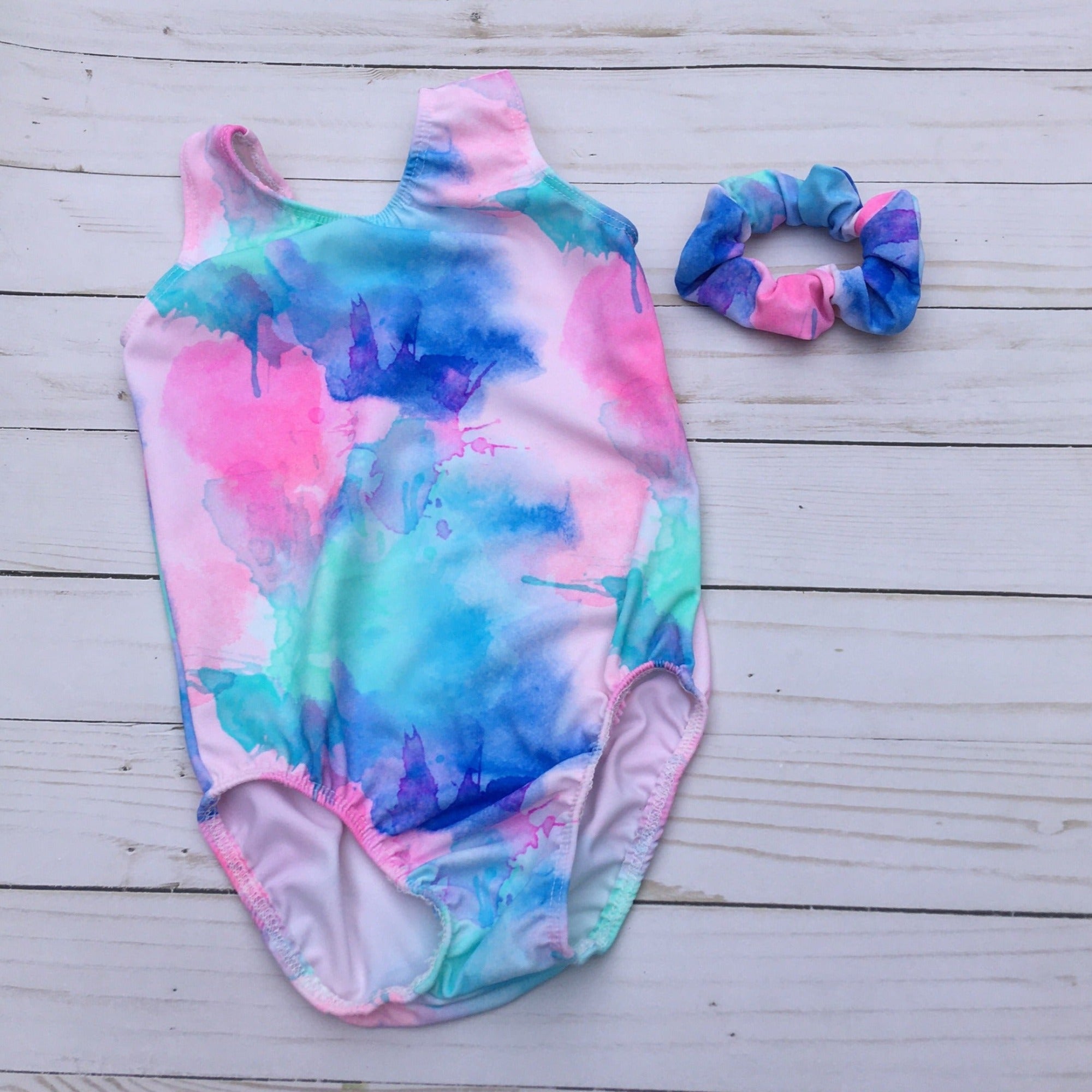 girls gymnastics tank leotard with soft pastel colors of pink, light pink, seafoam green, blue and purple in a splatter pattern.
