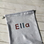 Load image into Gallery viewer, gymnastics grip bag in shiny silver fabric with rainbow sparkle personalization in block letters
