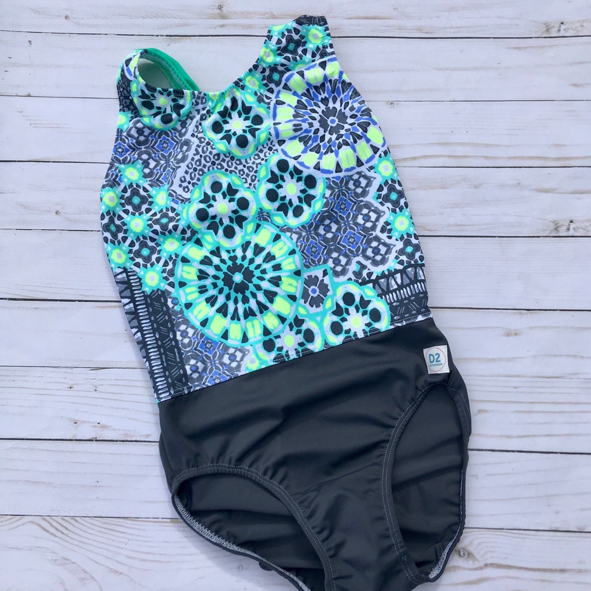 Gymnastics leotard in Pastel Mandala print with soft gray accented bottom.  Seaform green, white, gray, neon yellow and periwinkle colors make up the Mandala print.